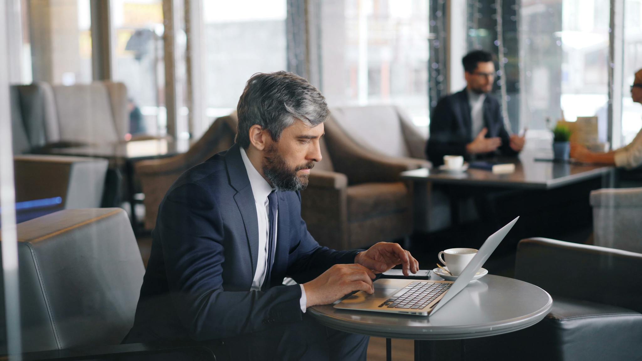 A man in a suit sitting at a table with a laptop